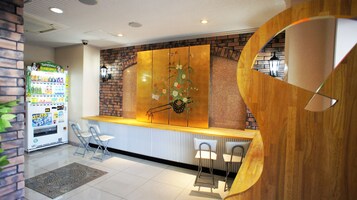 Un área de recepción con una máquina expendedora, un revestimiento decorativo y un detalle de madera.