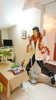 Una habitación con una mesa cubierta con un mantel beige, una planta pequeña y una estatua de una persona con un micrófono.