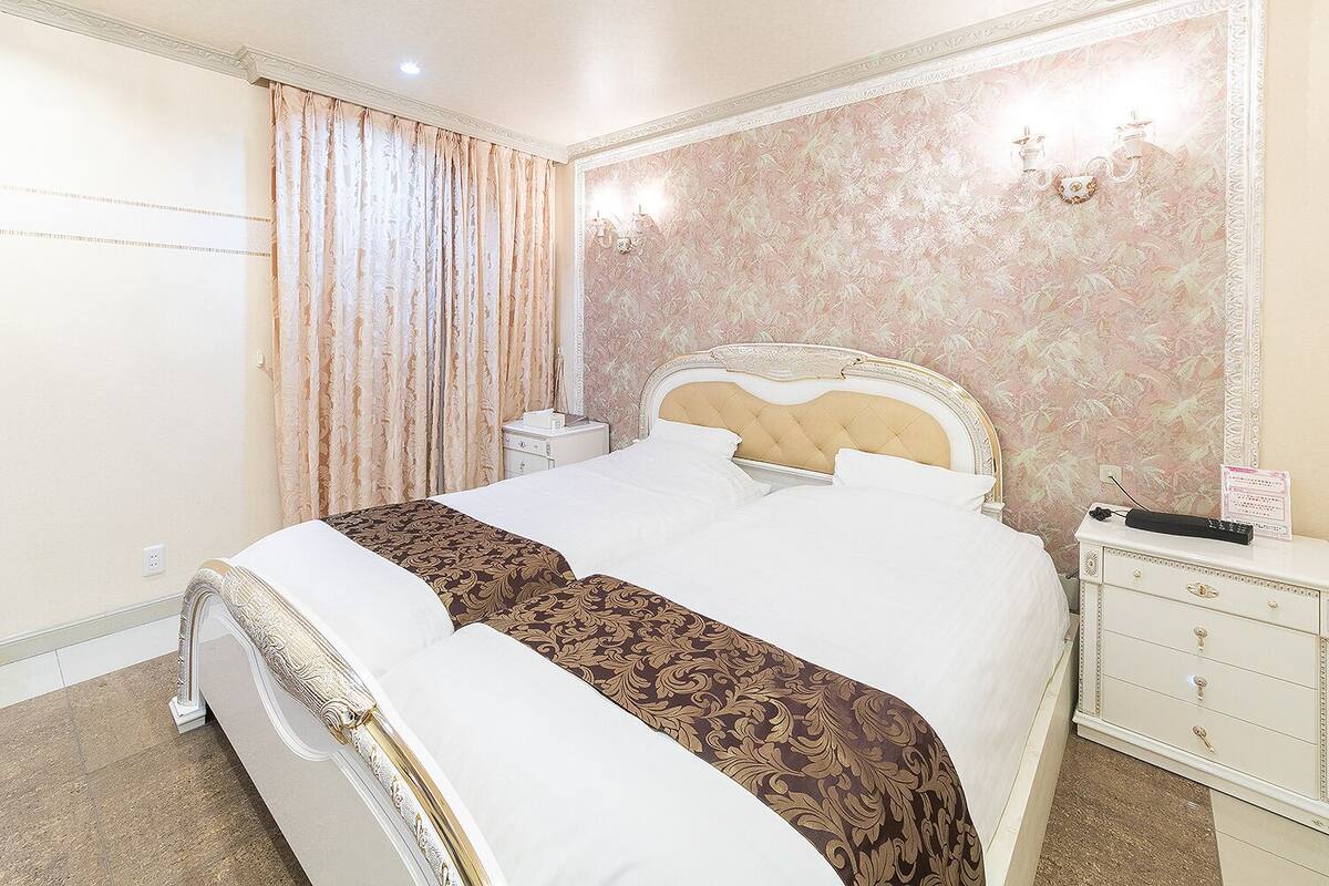 A hotel room with a large bed, a nightstand, and a dresser.