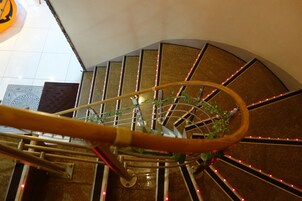 Una escalera de caracol con barandilla, pasamanos de metal y luces LED rojas.
