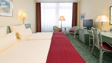 A hotel room with two beds, a desk with a computer, a chair, and a TV.