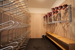 Un baño moderno con toalleros metálicos, un banco de madera y un espejo montado en la pared con adornos rojos.