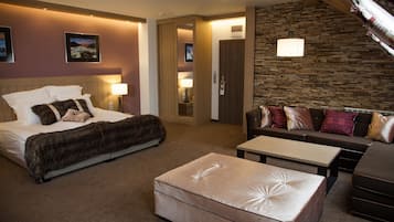 Una habitación de hotel con cama, sofá, mesa de centro y una pared decorativa de piedra.