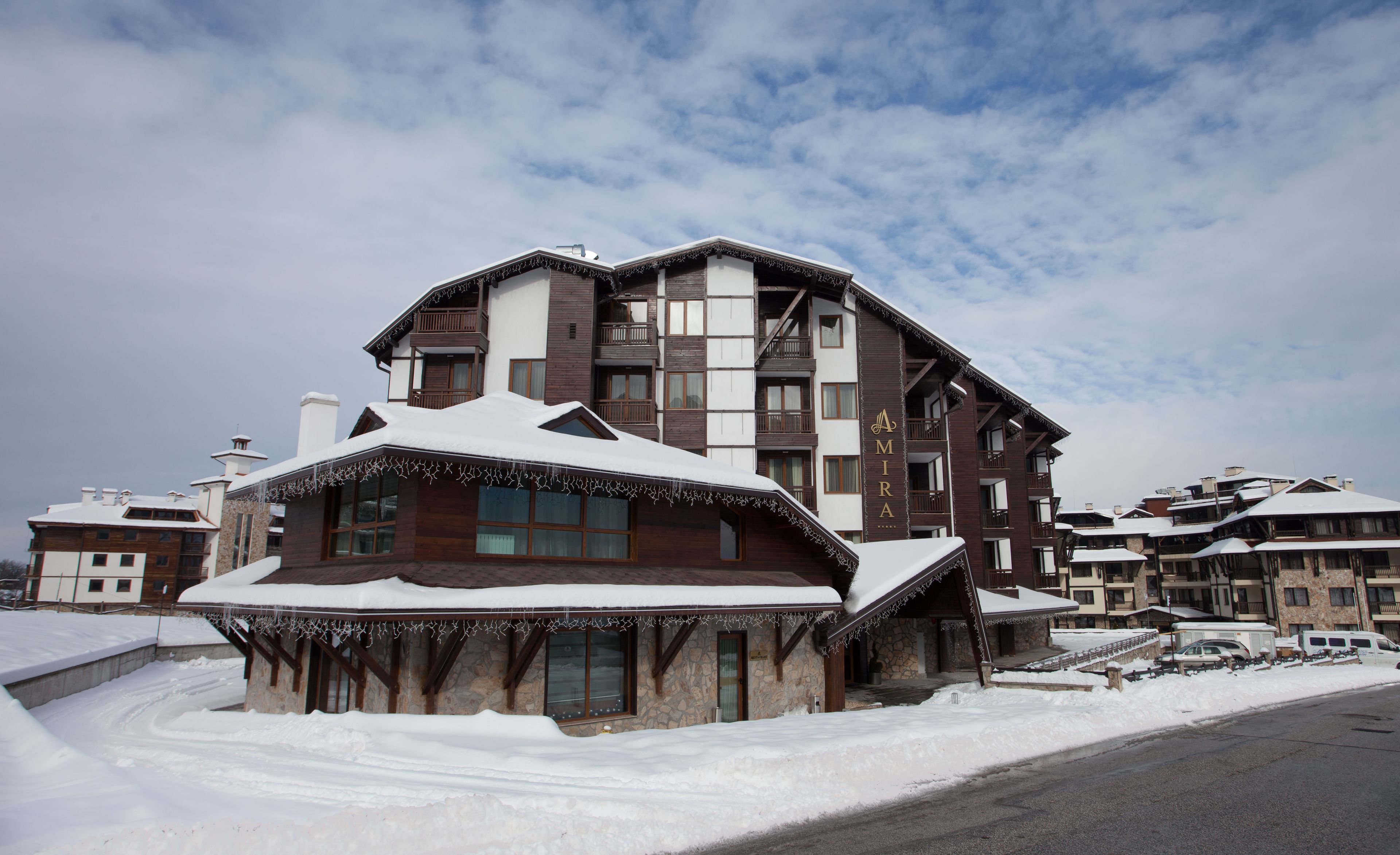 A multi-story hotel with a stone facade and wooden accents, featuring balconies and large windows.