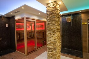 Un moderno espacio de spa con un pilar de piedra, una sauna y un baño de vapor.