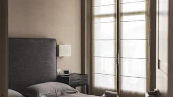 A hotel room with a bed, a nightstand, a lamp, and a window with blinds.