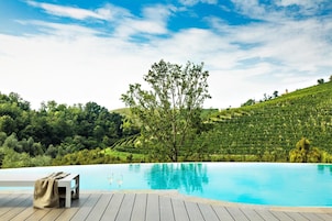 Una piscina con cubierta de madera y un banco, rodeada de abundante vegetación y colinas.