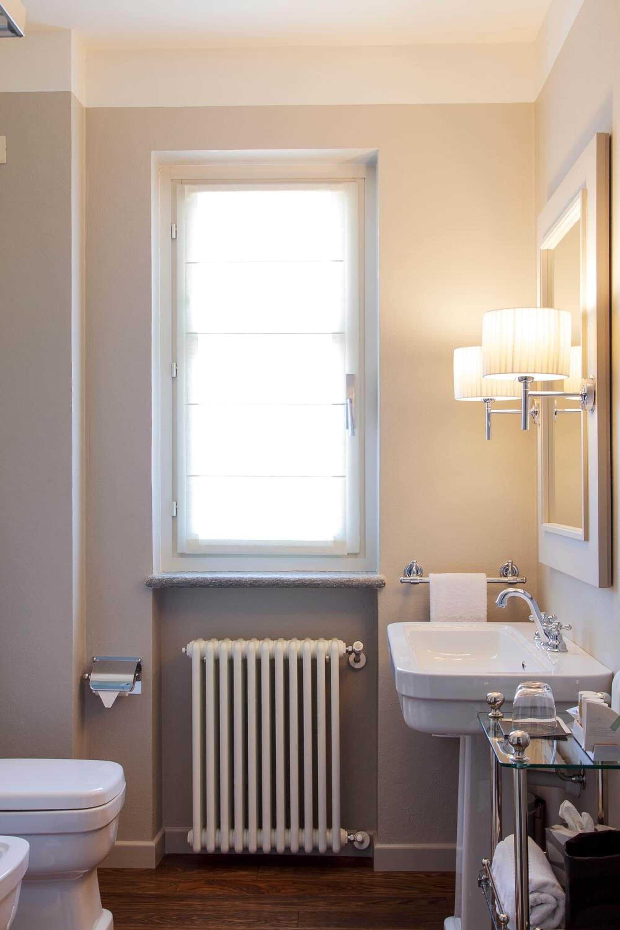 Ein Badezimmer mit Toilette, Waschbecken, Fenster und Heizkörper.