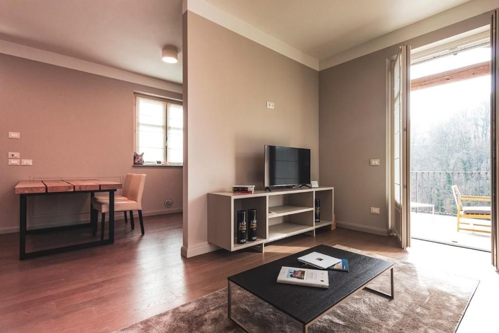 Una sala de estar con televisor, una mesa de centro, una estantería y un comedor con mesa y sillas.