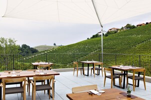 Un área de comedor al aire libre con mesas y sillas, con vistas a un viñedo.
