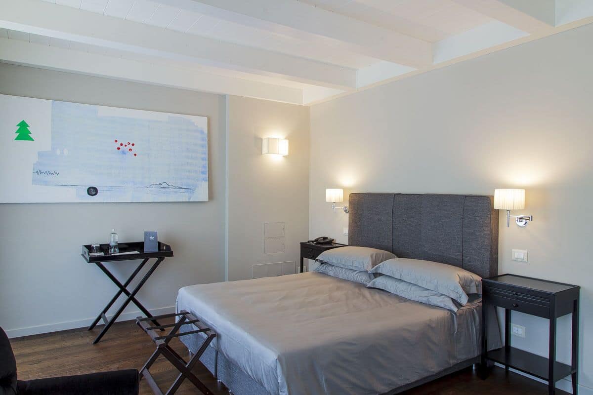 Una habitación de hotel moderna con cama, mesitas de noche, un escritorio y un mapa colgado en la pared.