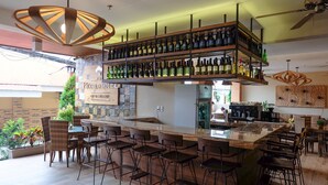 A bar area with multiple shelves of bottles, a central bar counter, and several bar stools.