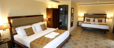 Une chambre d’hôtel avec un grand lit, un lit plus petit, une salle de bain et une table de chevet avec un téléphone.