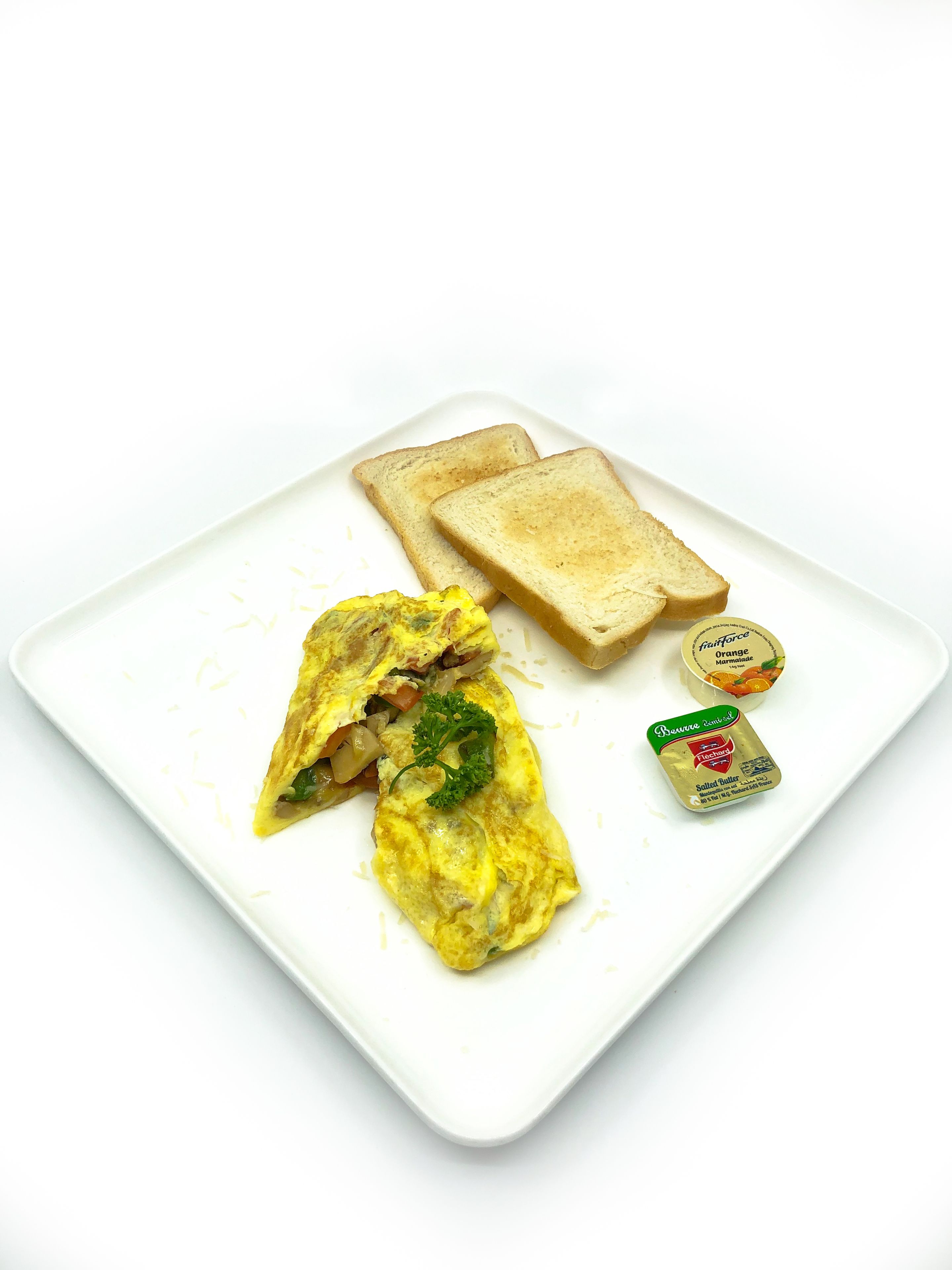 A plate with an omelette, two slices of toast, and two containers of butter.