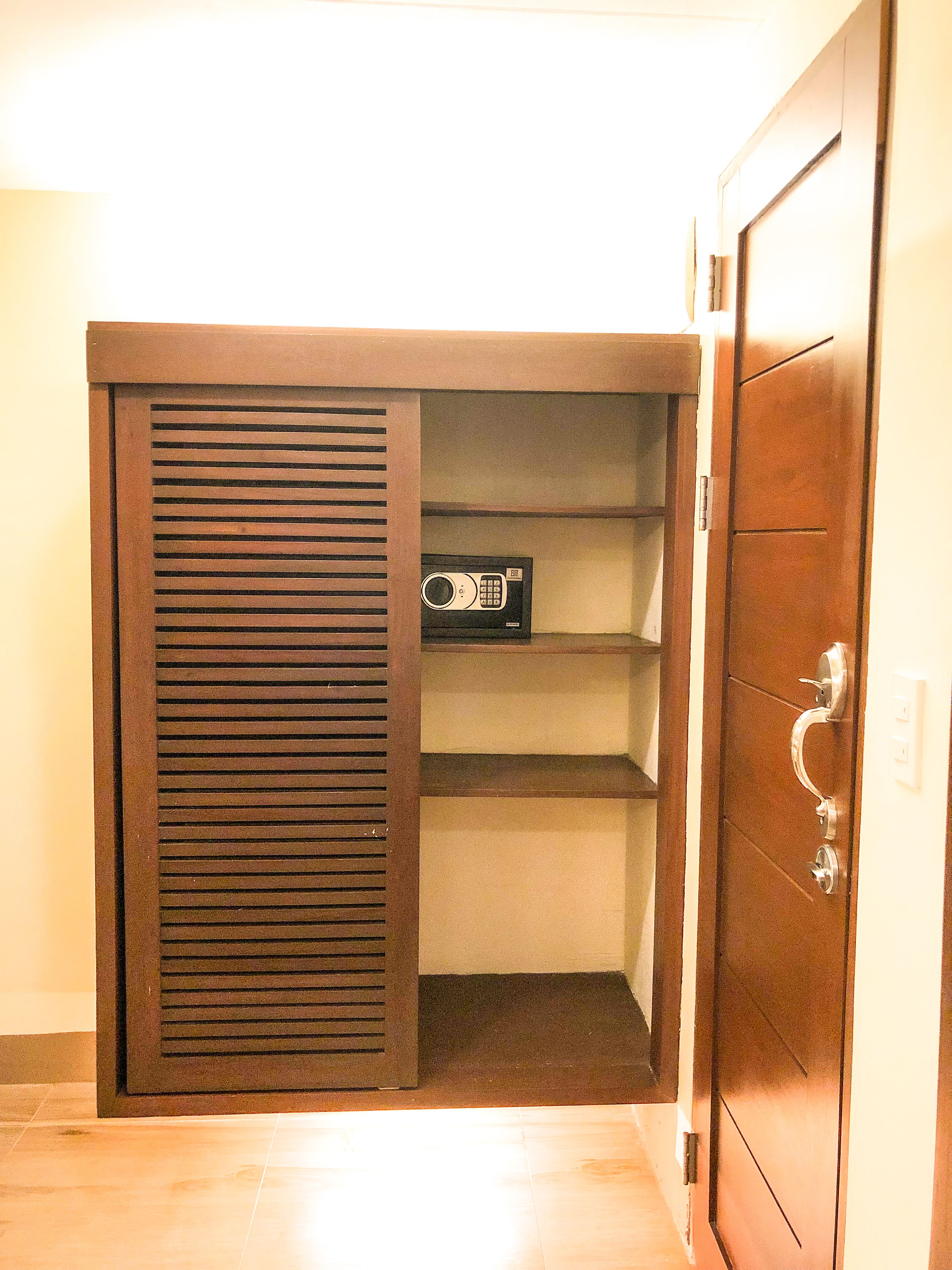A wooden wardrobe with a sliding door, a built-in microwave, and a metal handle.