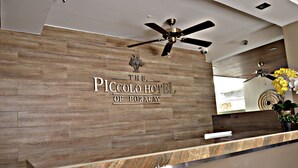 A reception desk with a wooden panel wall and a ceiling fan.