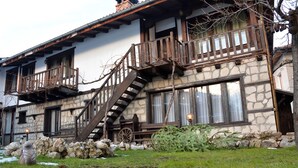 A stone building with wooden balconies and a staircase. - Trenchova Guest House (Bansko)