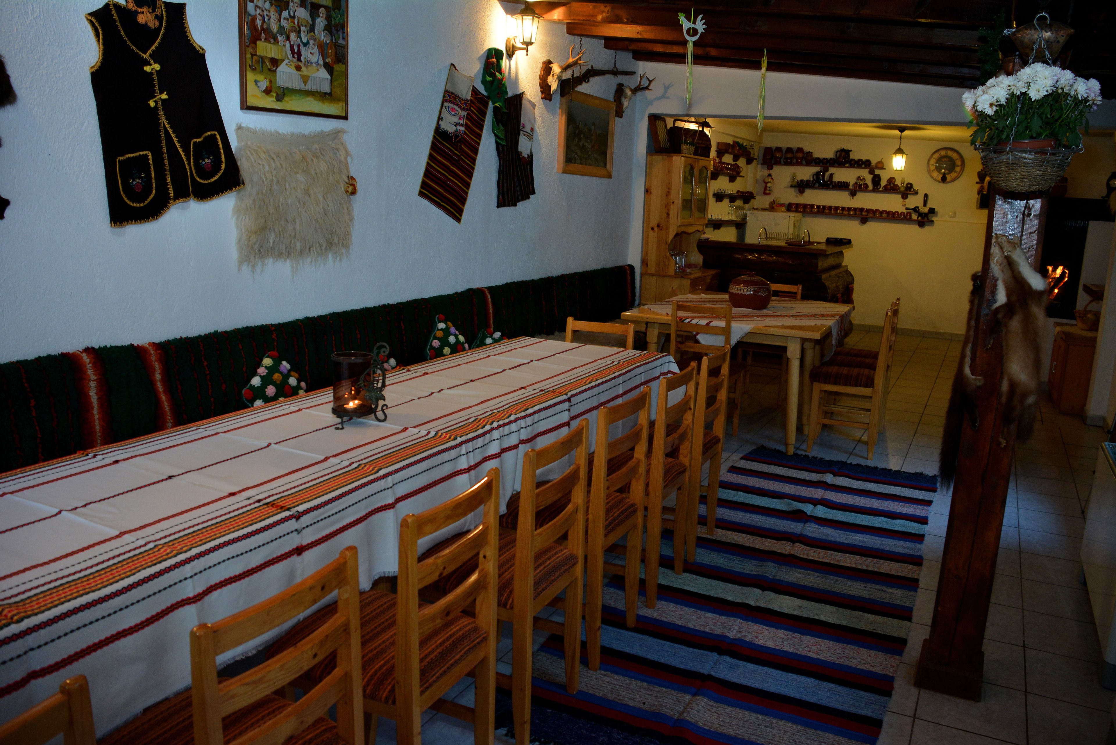 A dining area with a long table, wooden chairs, and a patterned tablecloth.