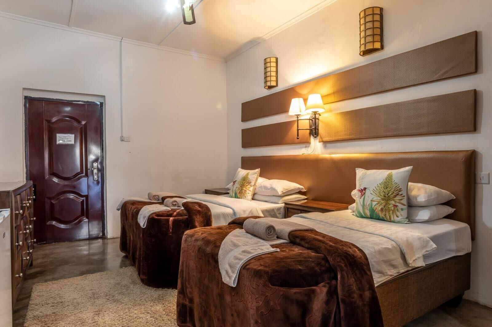 Habitación de hotel con dos camas, una puerta de madera y un pequeño escritorio.