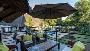 Un patio al aire libre con mobiliario de mimbre, una mesa de madera y un paraguas grande.