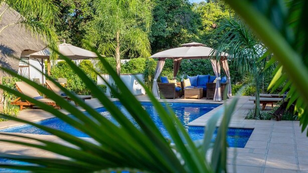 Un área de piscina con sillones de descanso y un pabellón.