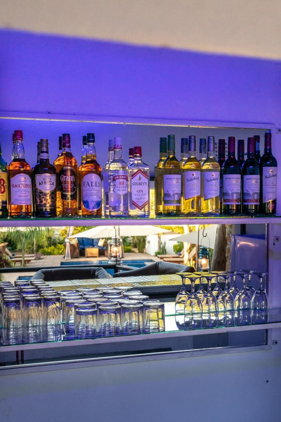 Een bar met flessen drank op planken en een presentatie van wijnglazen.