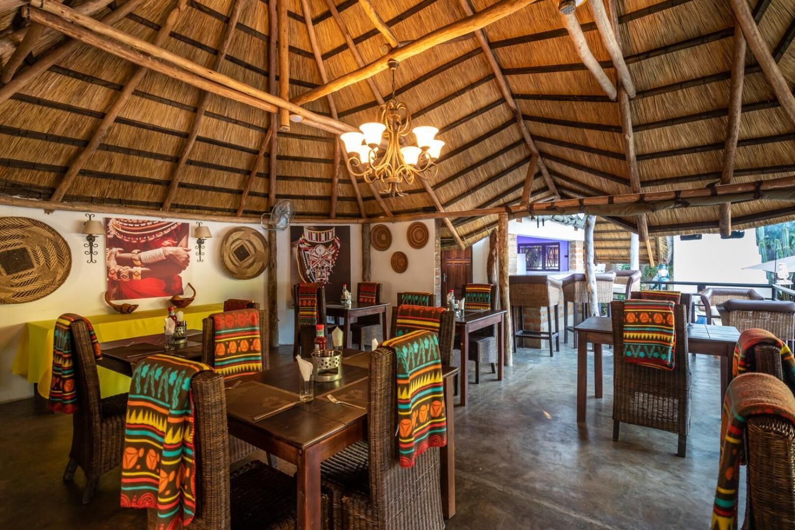 An open-air dining area with thatched roof, wicker furniture, and traditional decor.