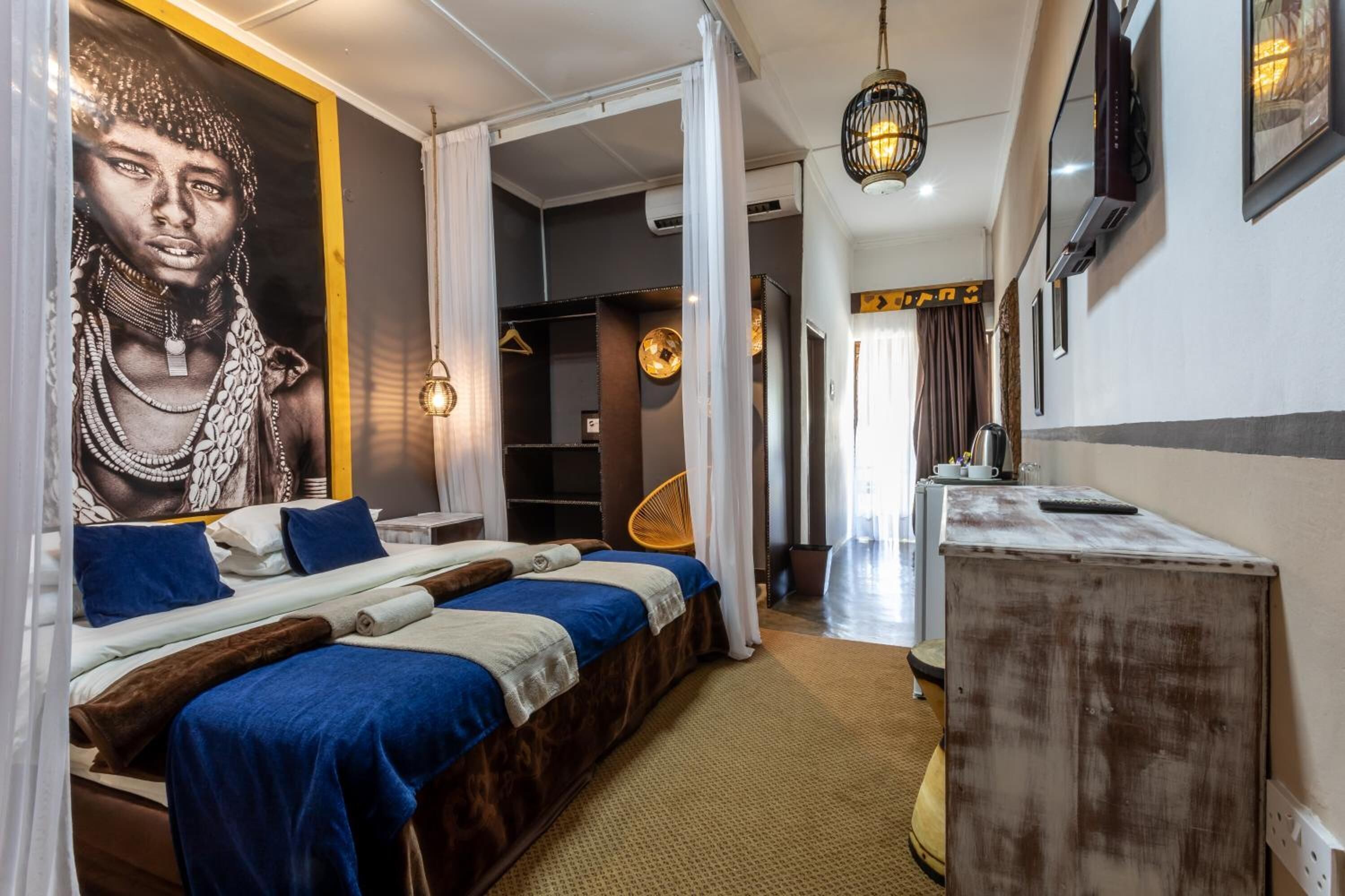 A modern hotel room with a large bed, a wardrobe, a mirror, and a wall-mounted TV.