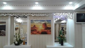 Una zona de recepció amb un quadre d'un paisatge desert, panells blancs decoratius i una pantalla de televisió.