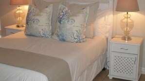 Un dormitorio con cama, dos mesitas de noche y cuadros en la pared.
