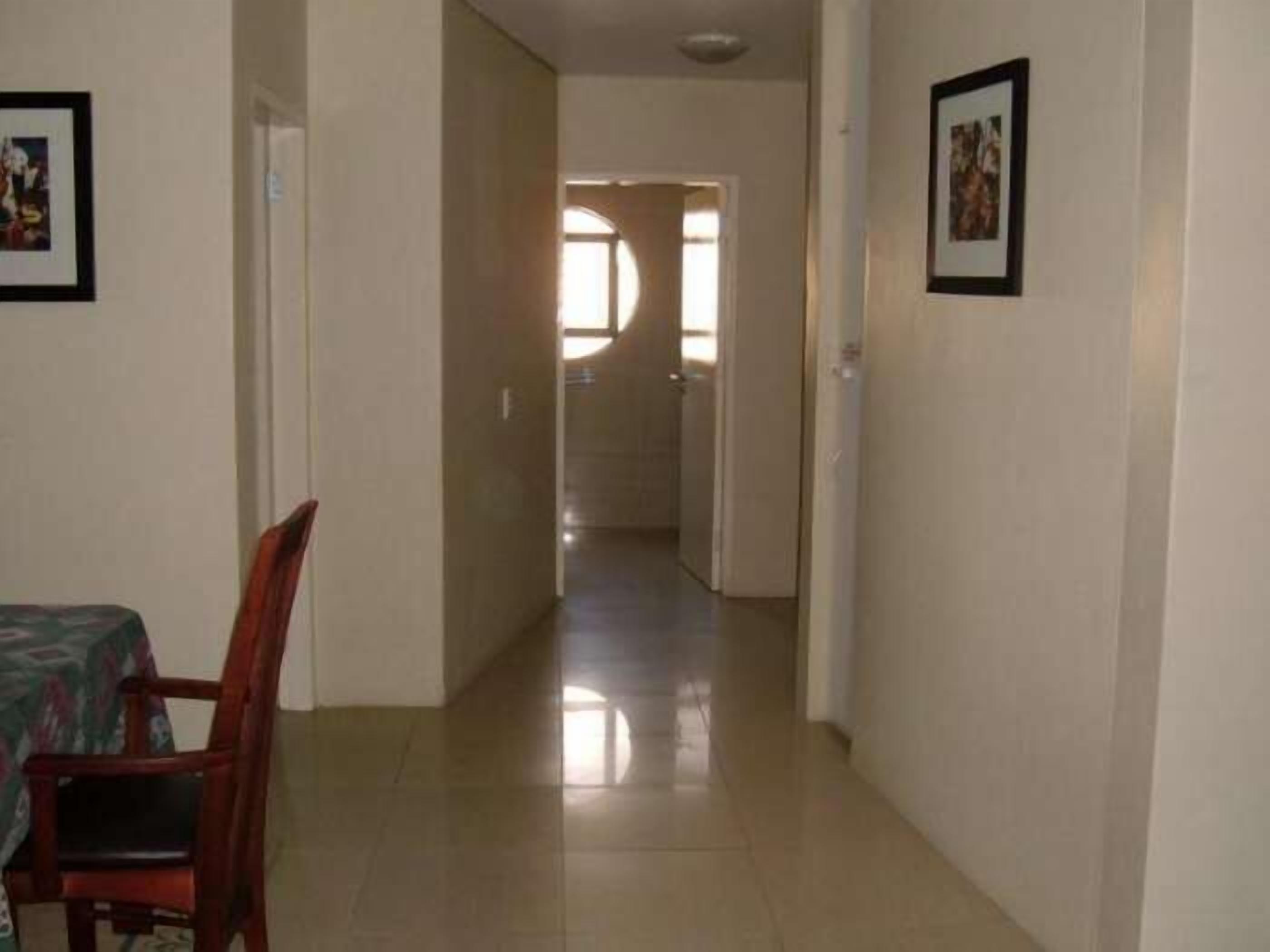 A hallway with a dining area on the left, featuring a table and chairs.