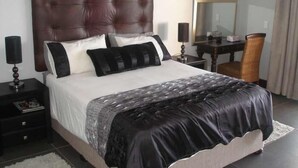 Ein Schlafzimmer mit einem großen Bett, einem Nachttisch, einem Schreibtisch und einem Stuhl.