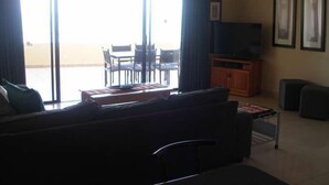 Ein Wohnzimmer mit einer Couch, einem Fernseher und einem Essbereich mit Stühlen und einem Tisch.
