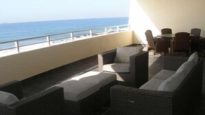 Ein Balkon mit Korbmöbeln, einem Tisch und Stühlen mit Blick auf das Meer.