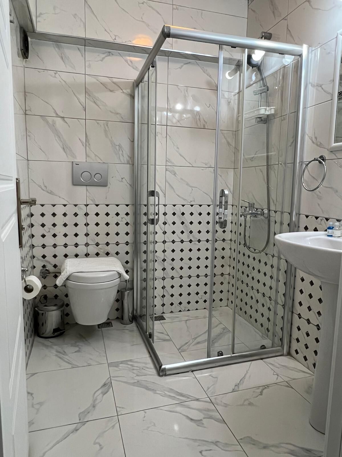 A modern bathroom with a glass-enclosed shower, a toilet, and a sink.