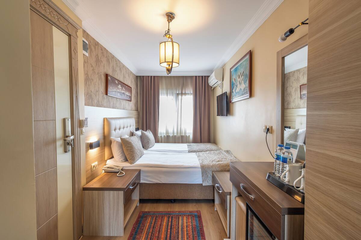 A hotel room with a large bed, bedside tables, a desk, and a mirror.