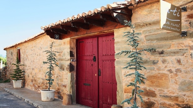 A rustic stone building with a red door, numbered 9, and a sign indicating it offers bed and breakfast services.