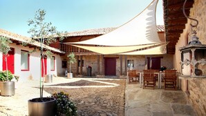 A courtyard with stone flooring, potted plants, and outdoor seating.