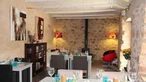 A dining area with a stone wall, modern chairs, and a fireplace.