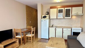 Ein kompakter Wohnbereich mit Küchenzeile, Essbereich, einer Couch und einem Fernseher.