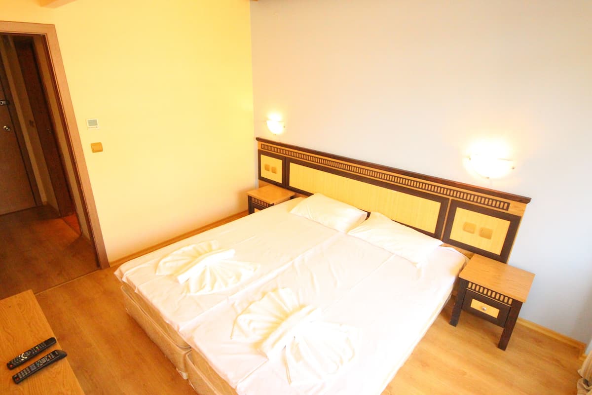 A large bed with white linens, two bedside tables, and a nightstand.