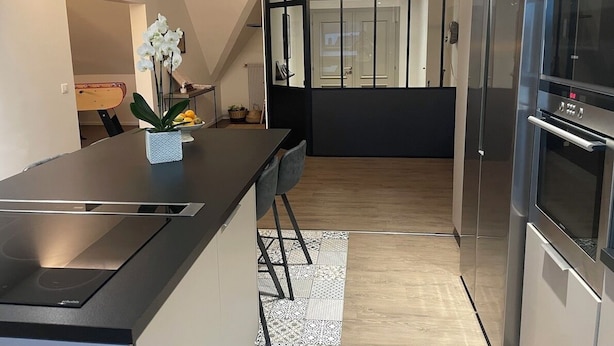 Una cocina moderna con una isla central, electrodomésticos de acero inoxidable y vistas al comedor.
