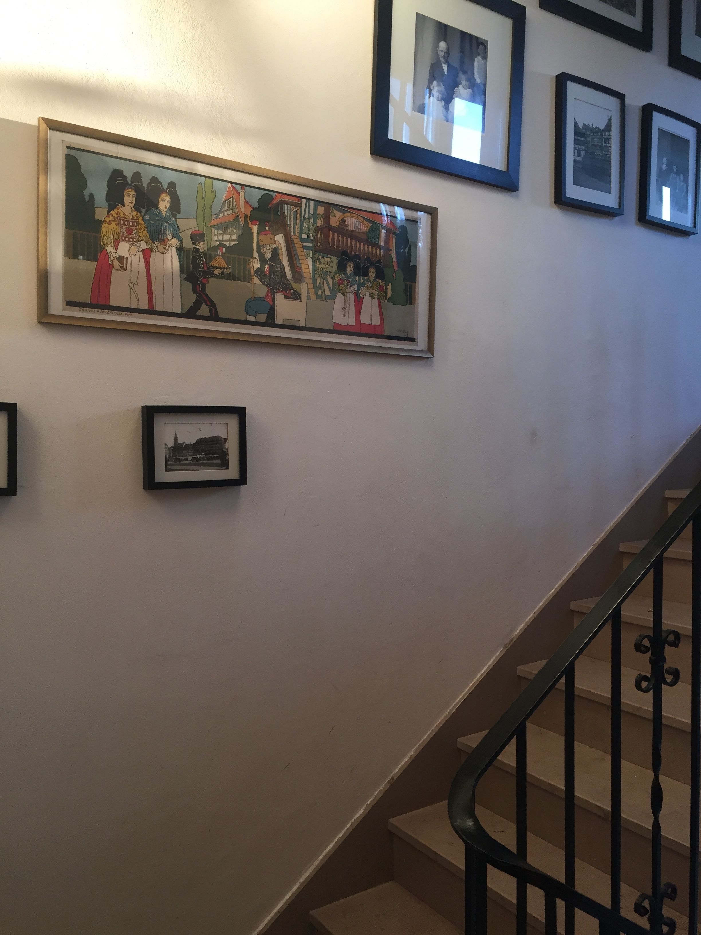 A staircase with a handrail and a wall with framed pictures.