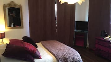 A bedroom with a bed, a mirror, a TV, and a dresser.