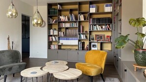 Una sala moderna con una estantería, un sillón amarillo y un sofá gris.