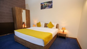 A neatly made bed with a yellow blanket and pillows, a wooden wardrobe, two bedside lamps, and a framed picture on the wall. - My Apartments Yerevan (Yerevan)