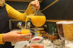A person pouring orange juice into a glass. - My Apartments Yerevan (Yerevan)