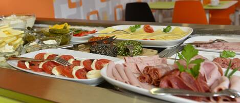 A buffet with various food items including meats, cheeses, and vegetables.