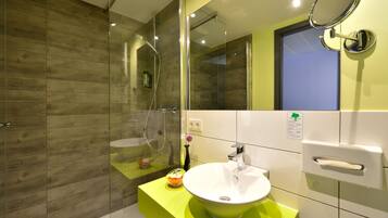 Un baño moderno con mampara de ducha de vidrio, un lavamanos blanco y un espejo.