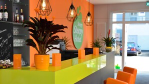 A reception area with a bright orange desk, a sign reading "Sleeping Hotel," and a view of the street outside.